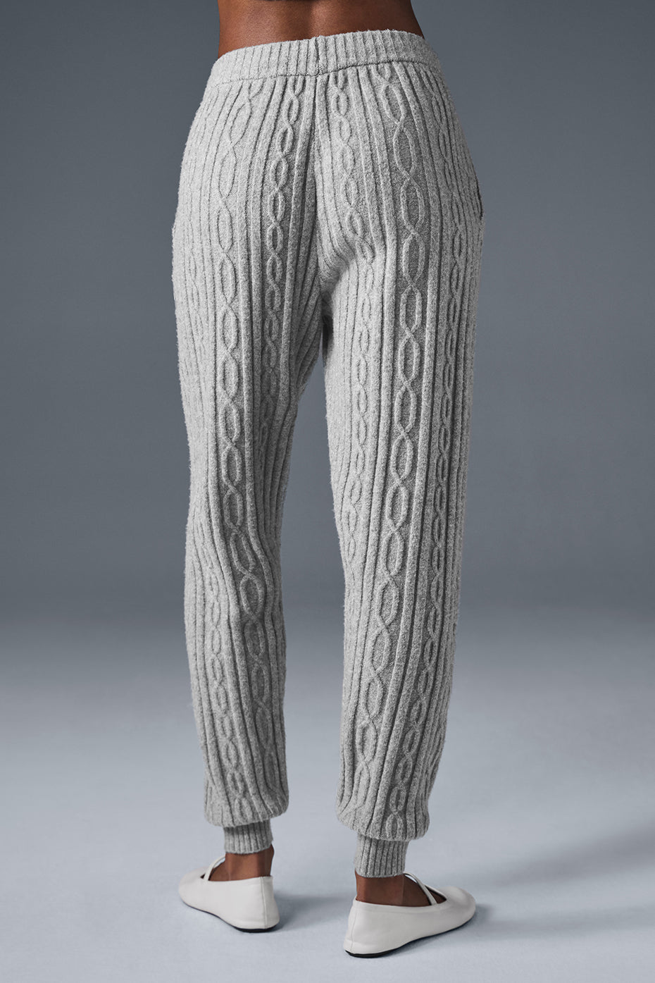 Model wearing cozy lounge pants by the fireplace, showcasing winter style.