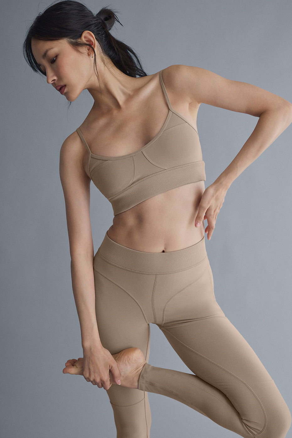 Model wearing full-length leggings with contrasting ribbed panels and matching sports bra