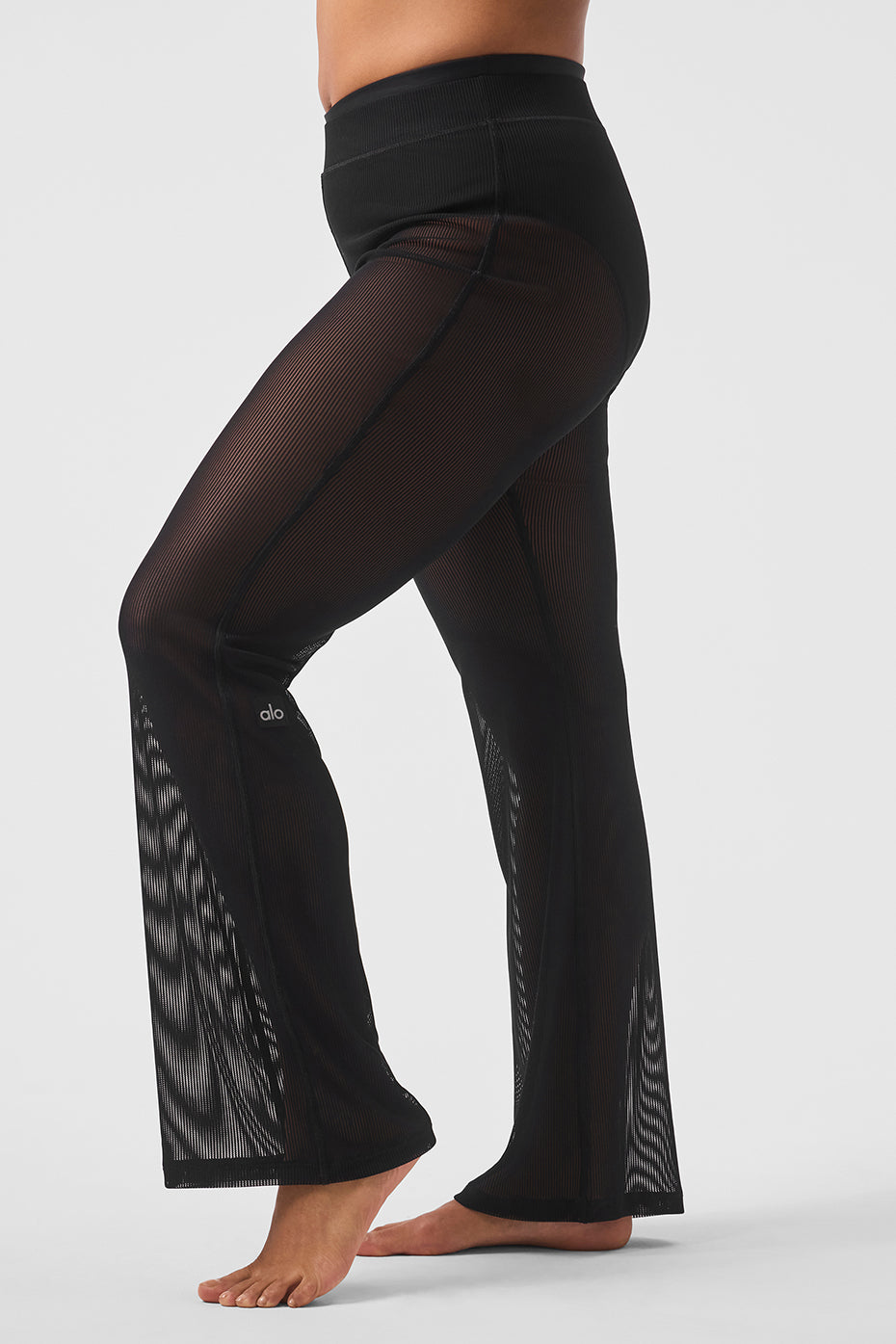 Model wearing high-waisted black mesh flare pants with sandals