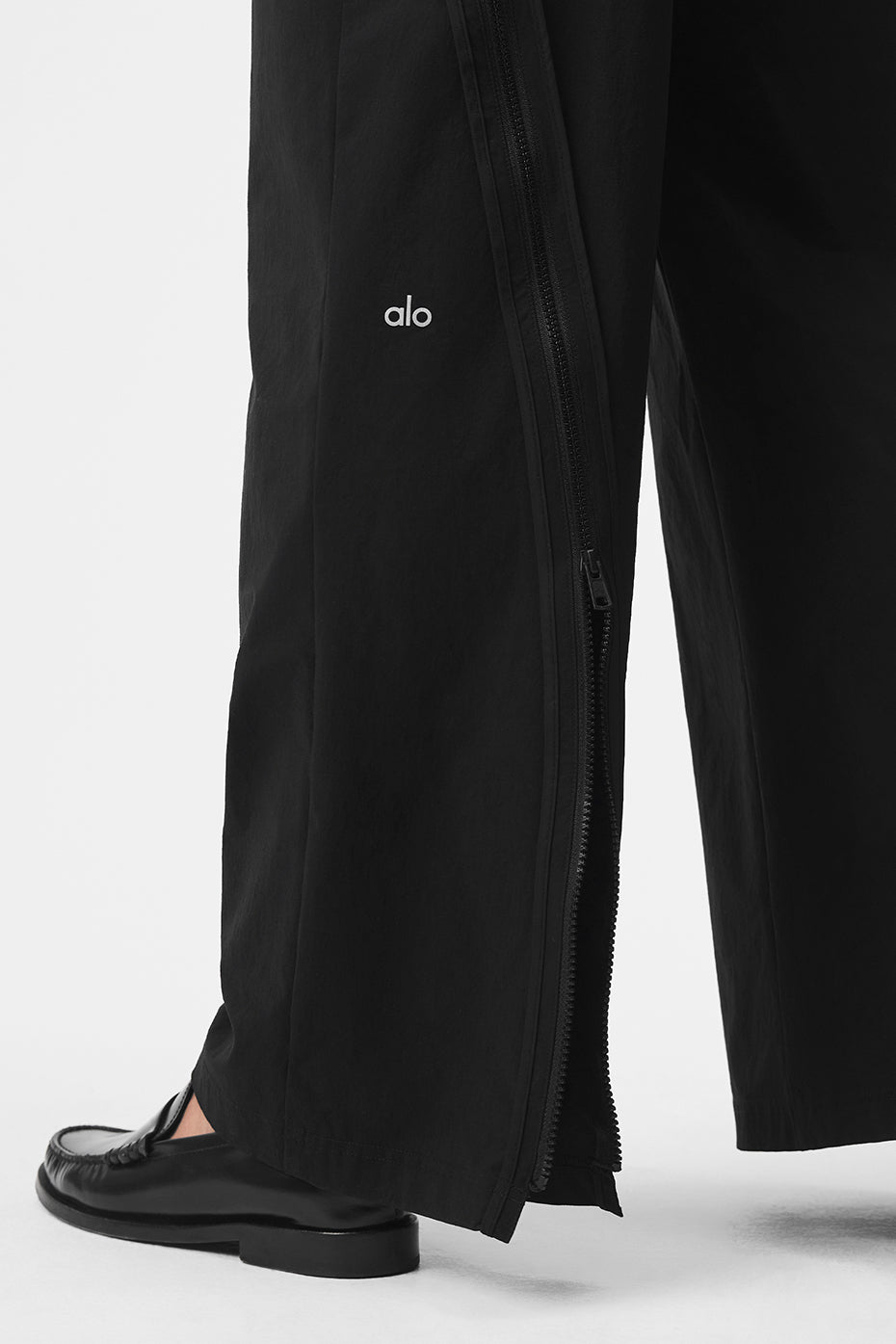 Close-up of zipper hem on black dress pants for men, showing customization options