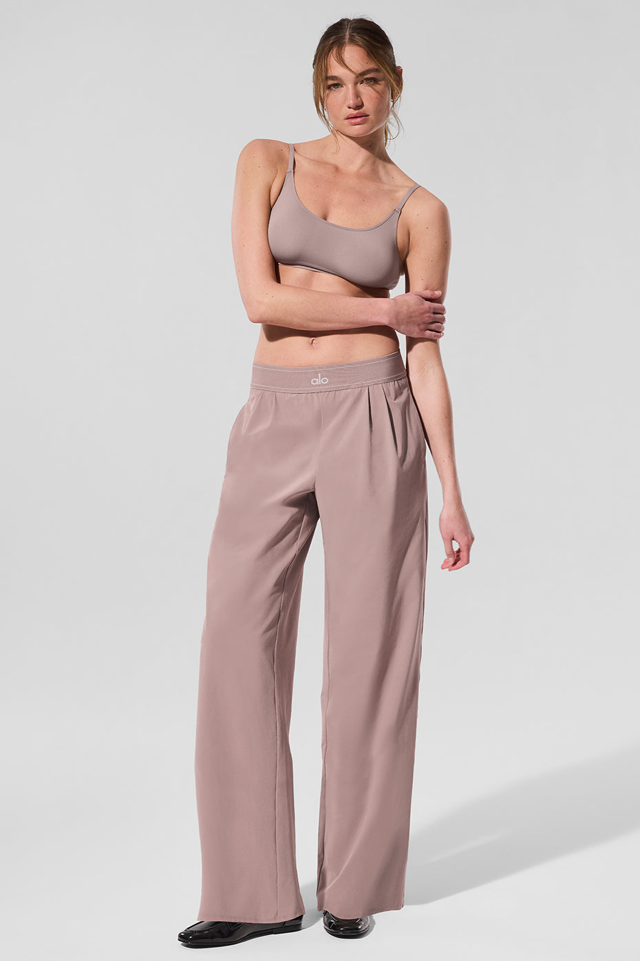 Close-up of the front pleats and side pockets on taupe fashion pants.