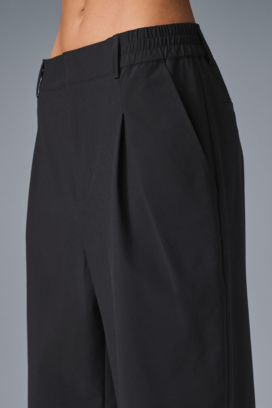 Black wide-leg pants draped on a hanger, showing pleated front detail