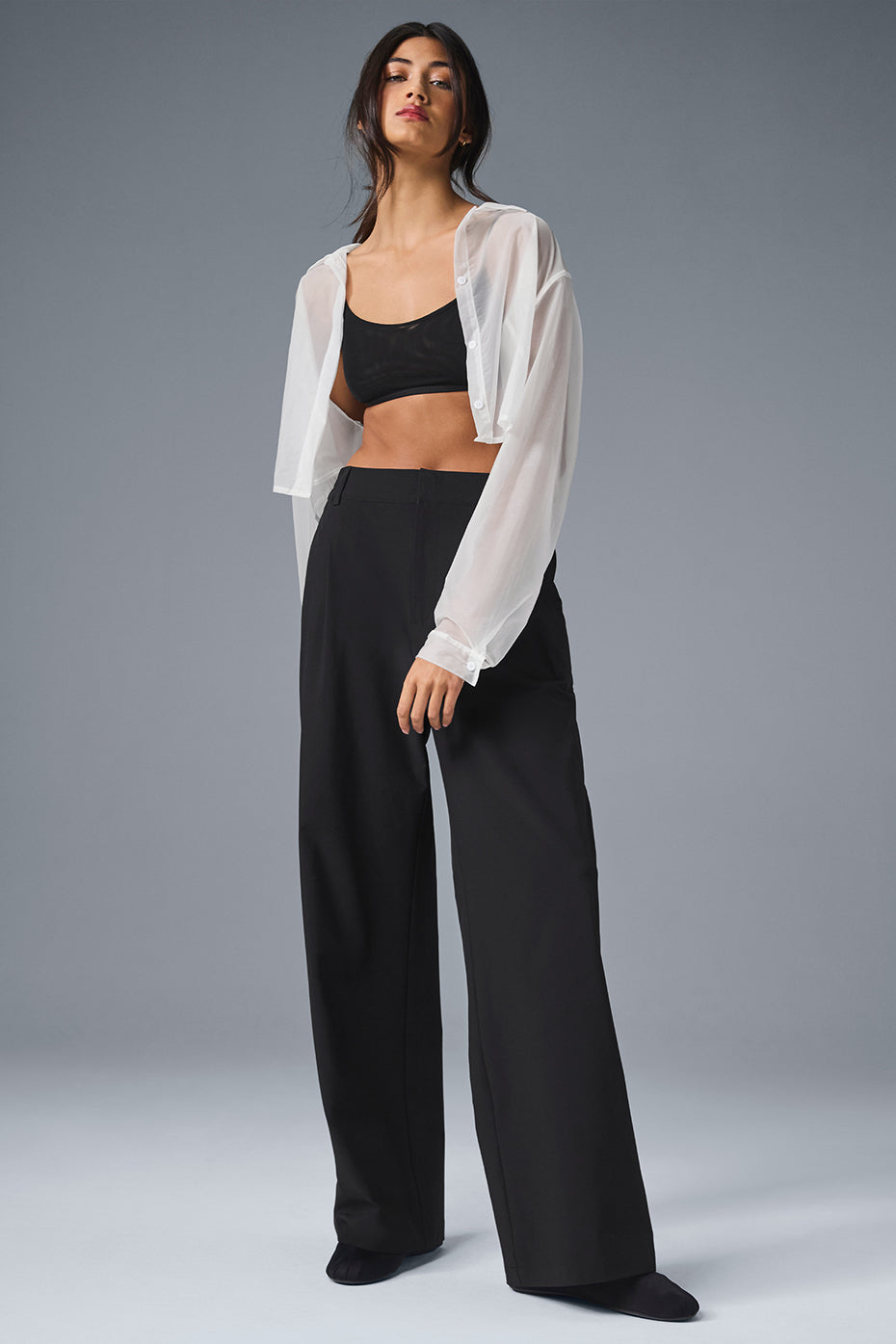 Black wide-leg pants draped on a hanger, showing pleated front detail