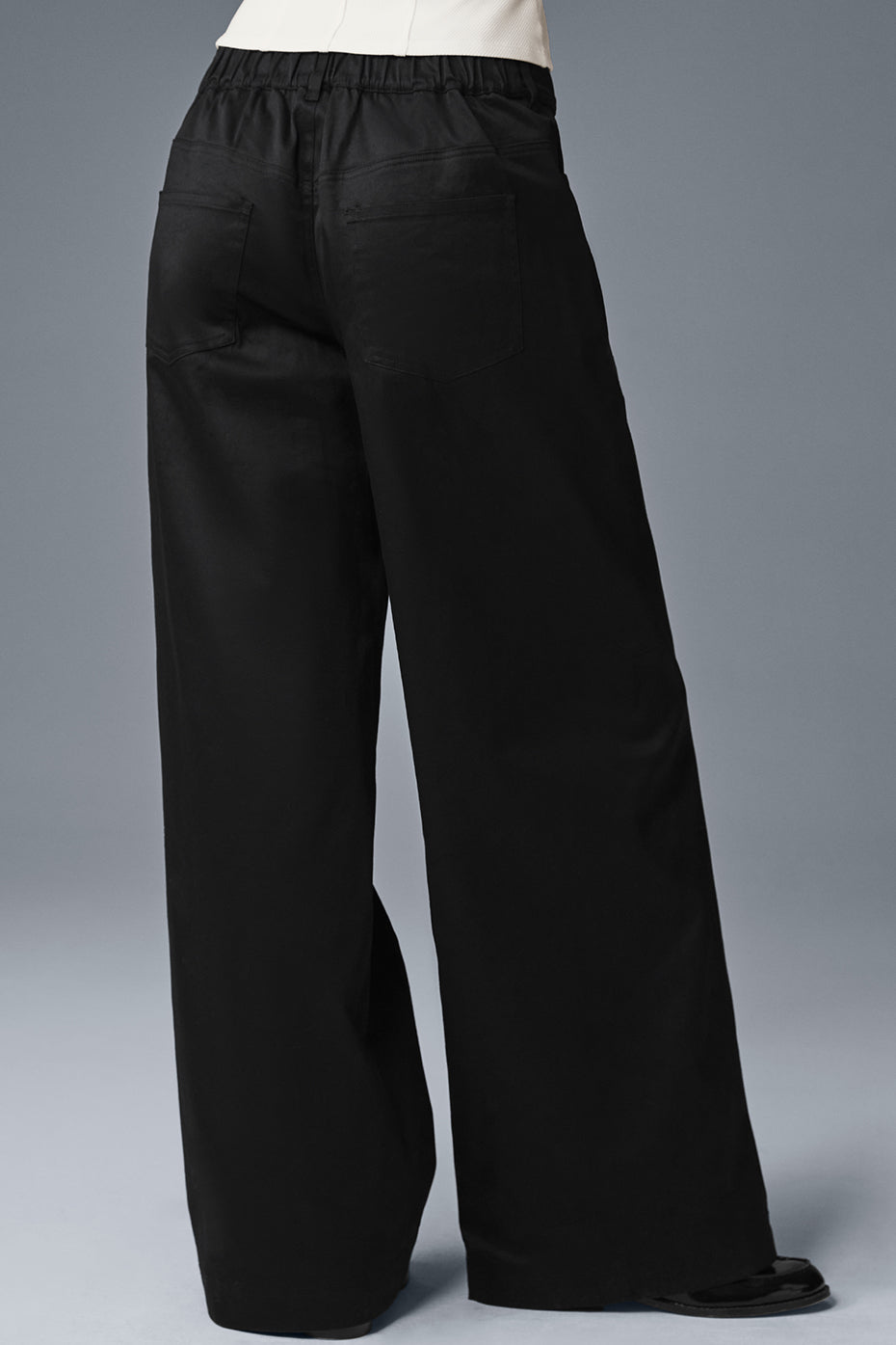 Model wearing black trousers at a casual outdoor event.