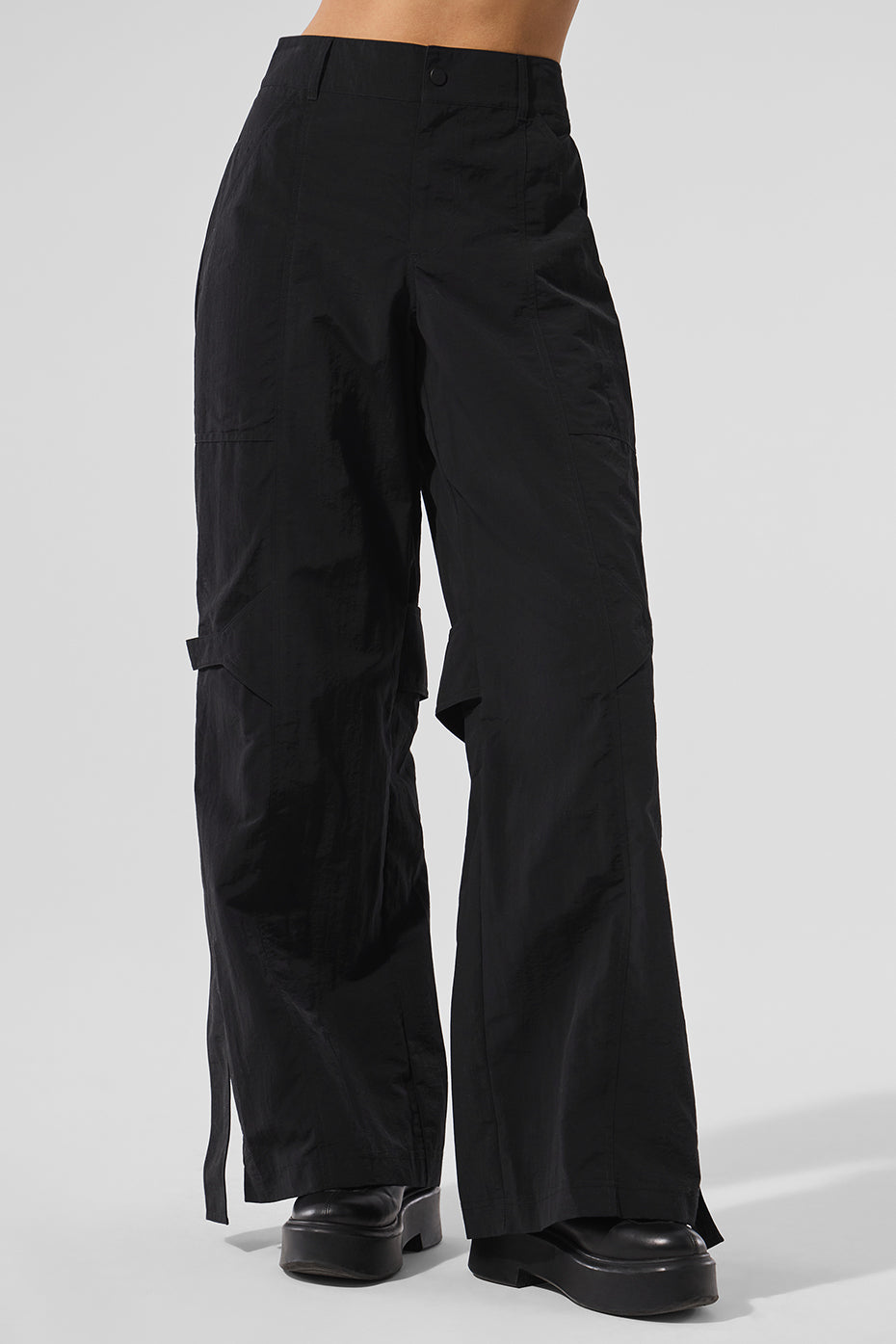 Black relaxed fit trousers showcasing draping side buckles.