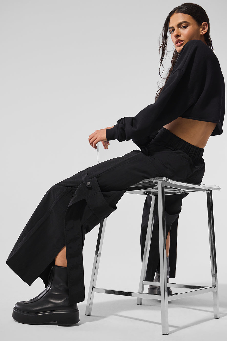 Black relaxed fit trousers showcasing draping side buckles.