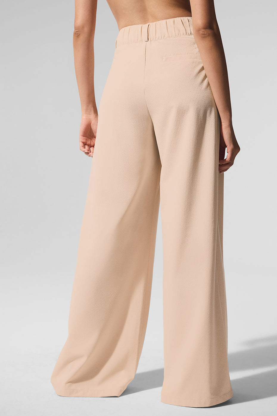 Close-up of high-waist pleated trousers showing the lightweight fabric and pleats