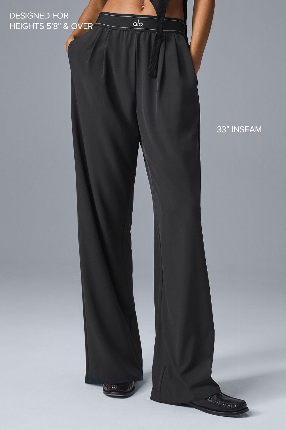 Close-up of pleated detail and elastic waistband on black trousers