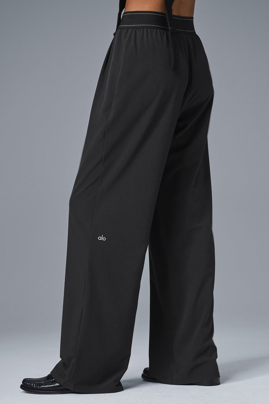 Close-up of pleated detail and elastic waistband on black trousers