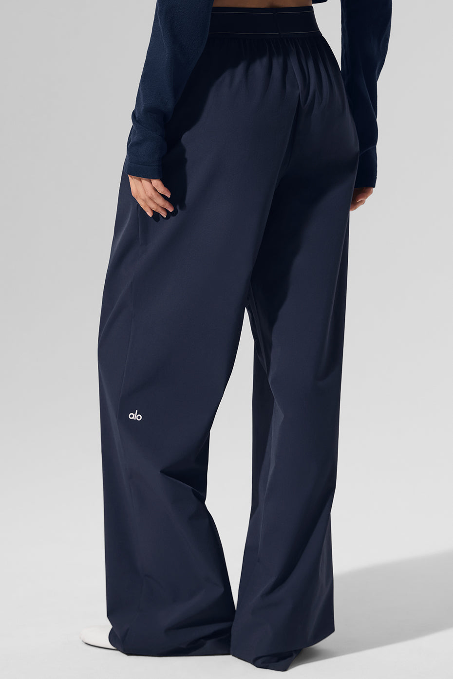 Side view of navy trousers displaying loose, straight-leg fit.