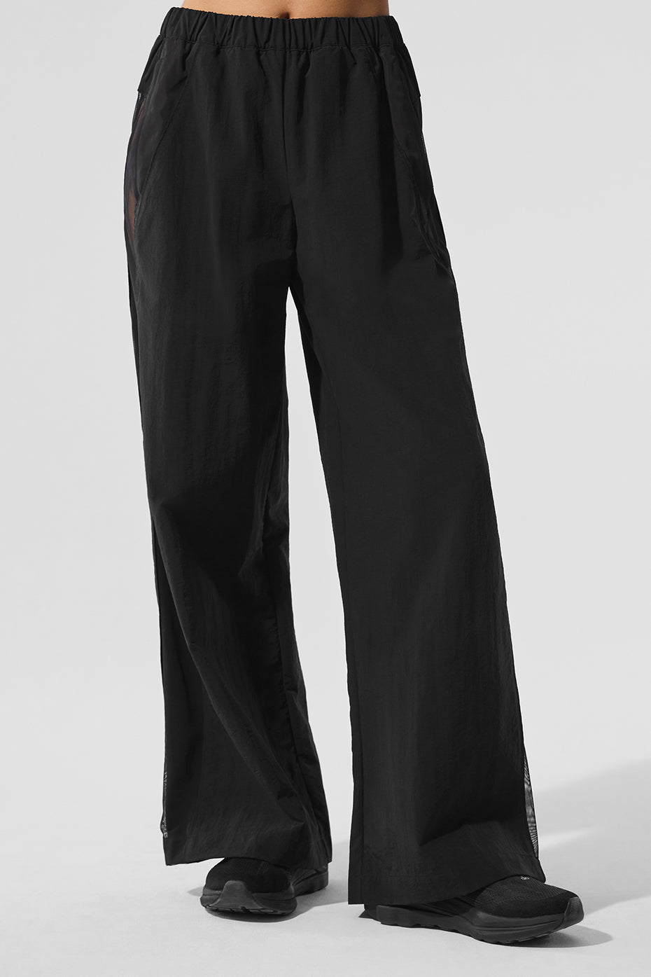Front view of black high-waist track pants with mesh detailing.