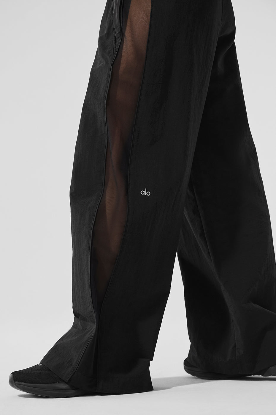 Model wearing black high-waist track pants in an urban setting.