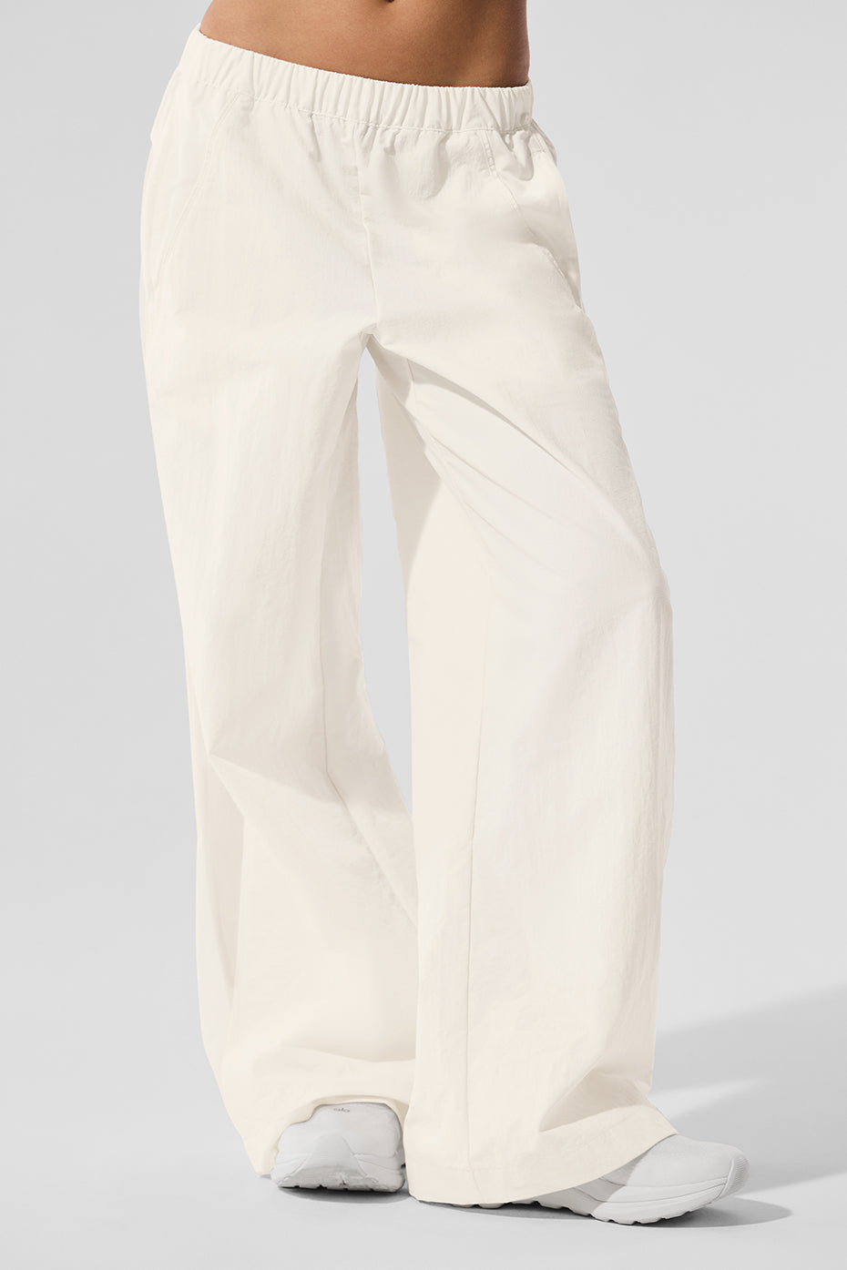 Front view of ivory high-waist wide leg track pants in a casual setting.