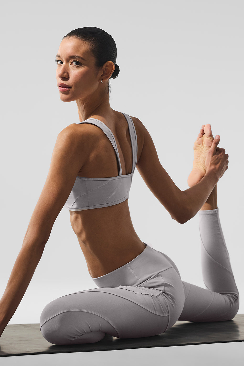 Model doing yoga in grey wide-leg yoga pants under sunlight