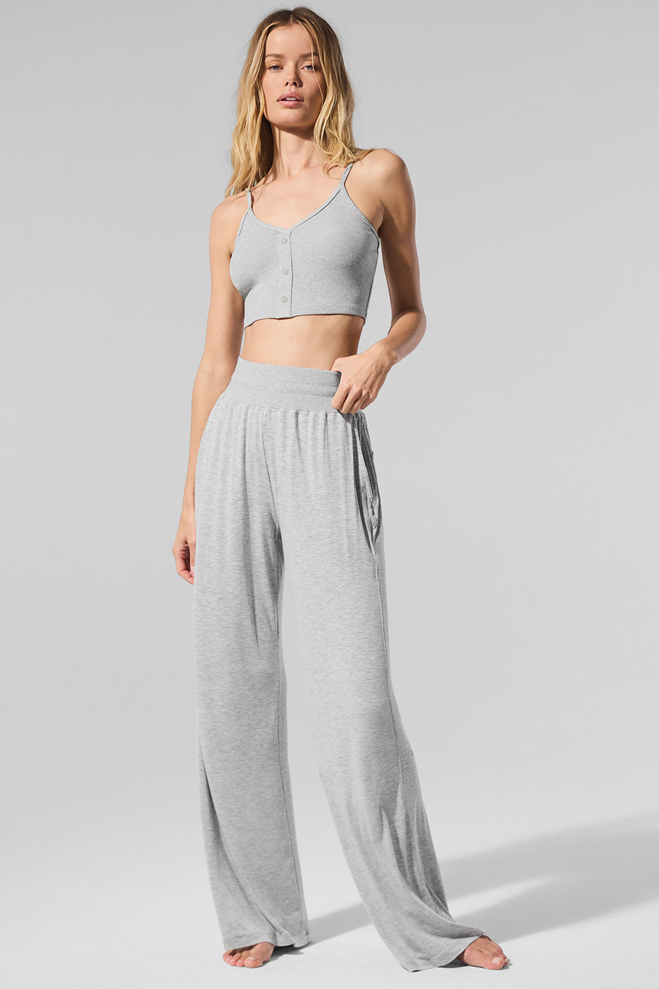 Side angle of black flare pants styled with white tank in a cozy home setting