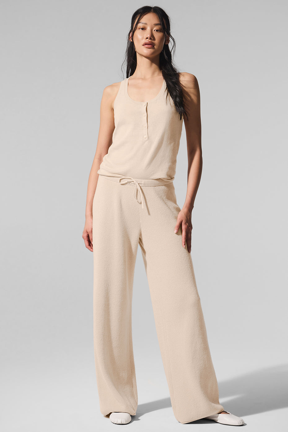Macadamia sweater pants folded beside sunglasses and woven beach tote