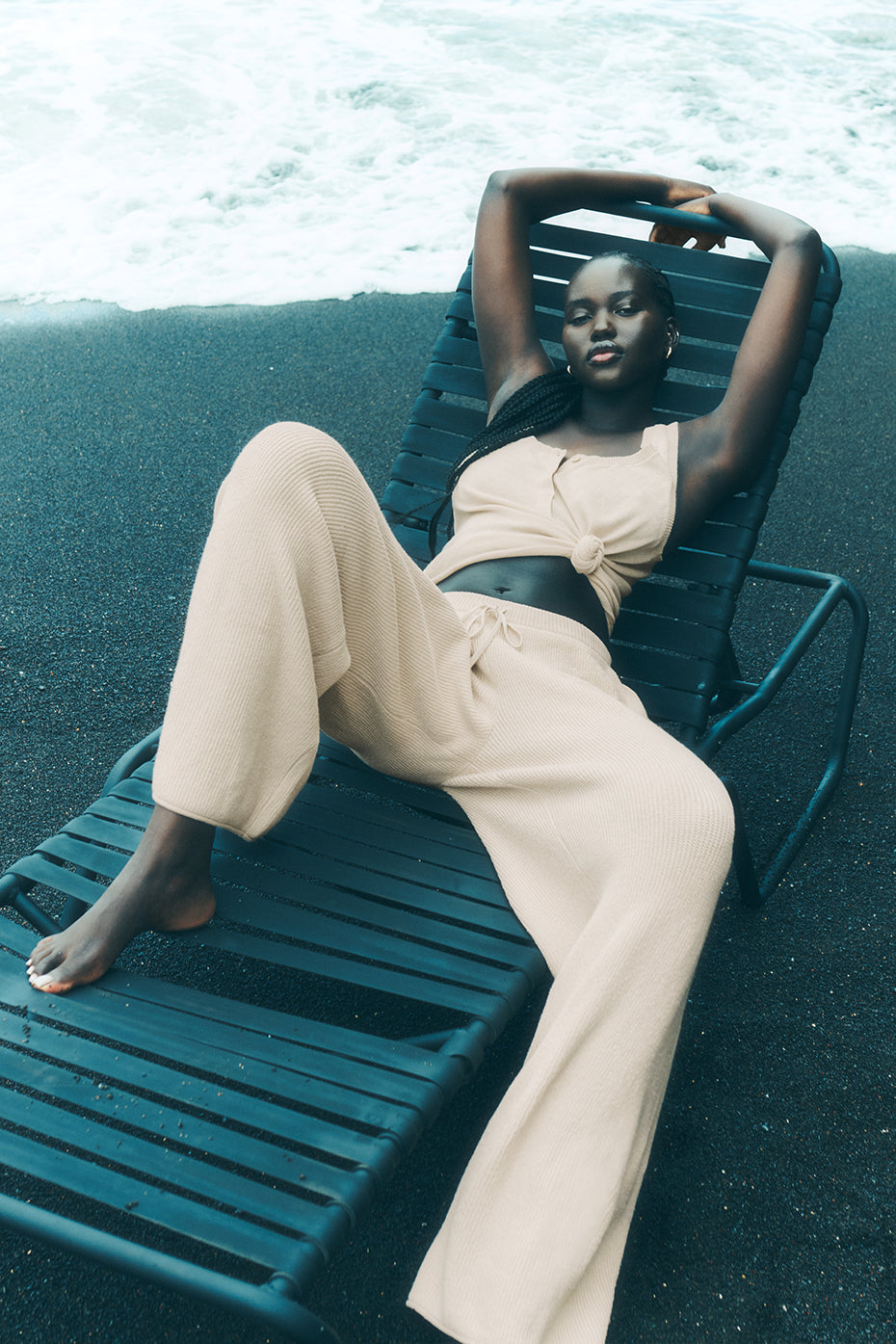 Macadamia sweater pants folded beside sunglasses and woven beach tote