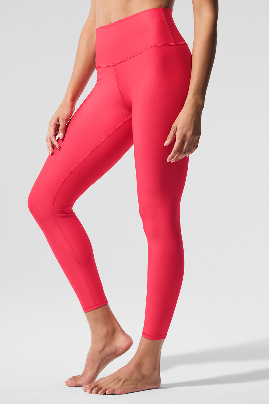 Woman wearing candy red Airlift leggings in a yoga pose, highlighting the compression fit.