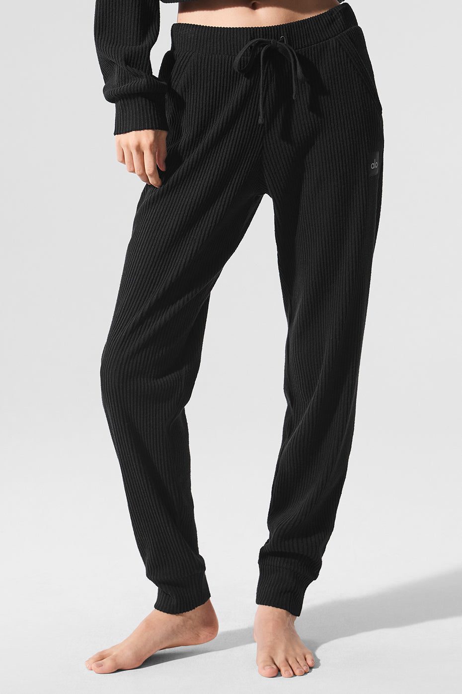 Model wearing black wide leg sweatpants with a white tee, urban backdrop