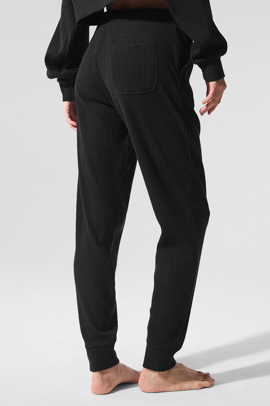 Back view of luxury sweatpants showing tapered ankle cuffs, styled with boots