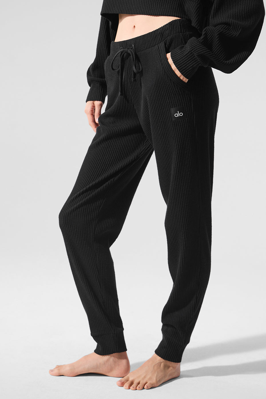 Model wearing black wide leg sweatpants with a white tee, urban backdrop