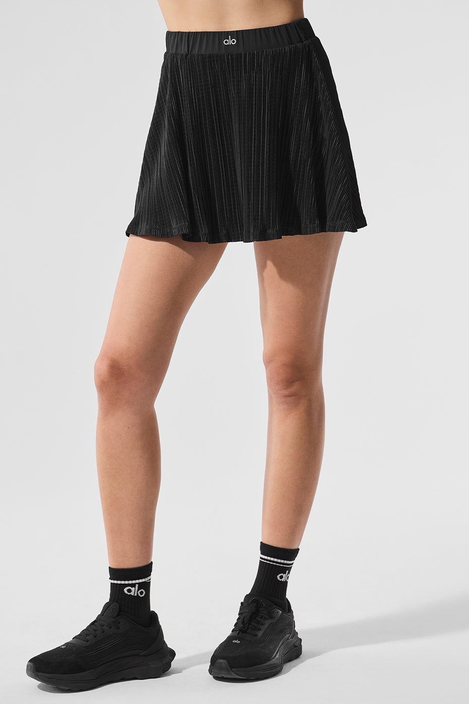 Front view of the elegant micro plisse white tennis skirt paired with a sports bra.