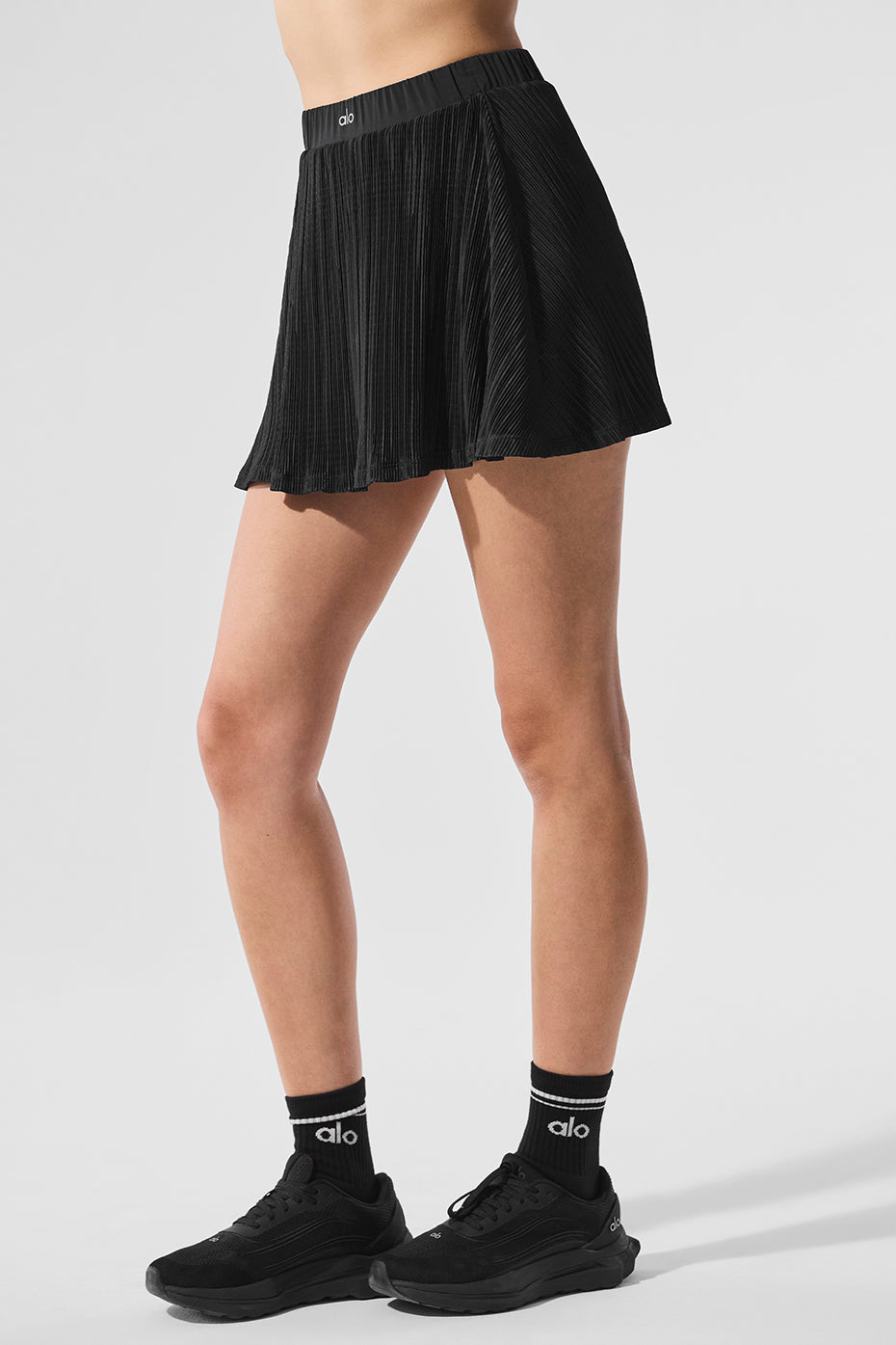 Front view of the elegant micro plisse white tennis skirt paired with a sports bra.