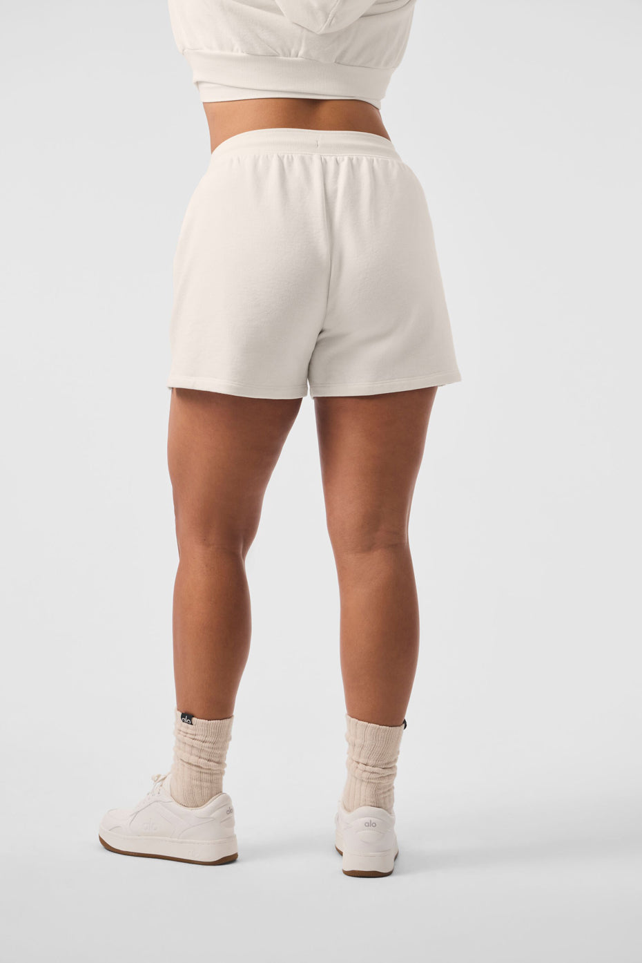 Front view of chic high rise sweat shorts in ivory, showcasing side pockets.