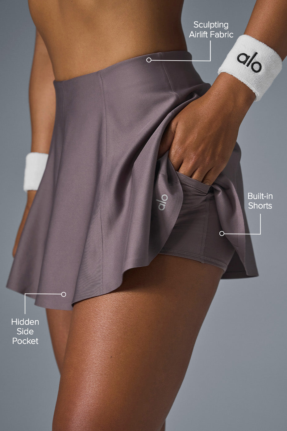 Woman wearing the Airlift tennis skirt while serving on the court