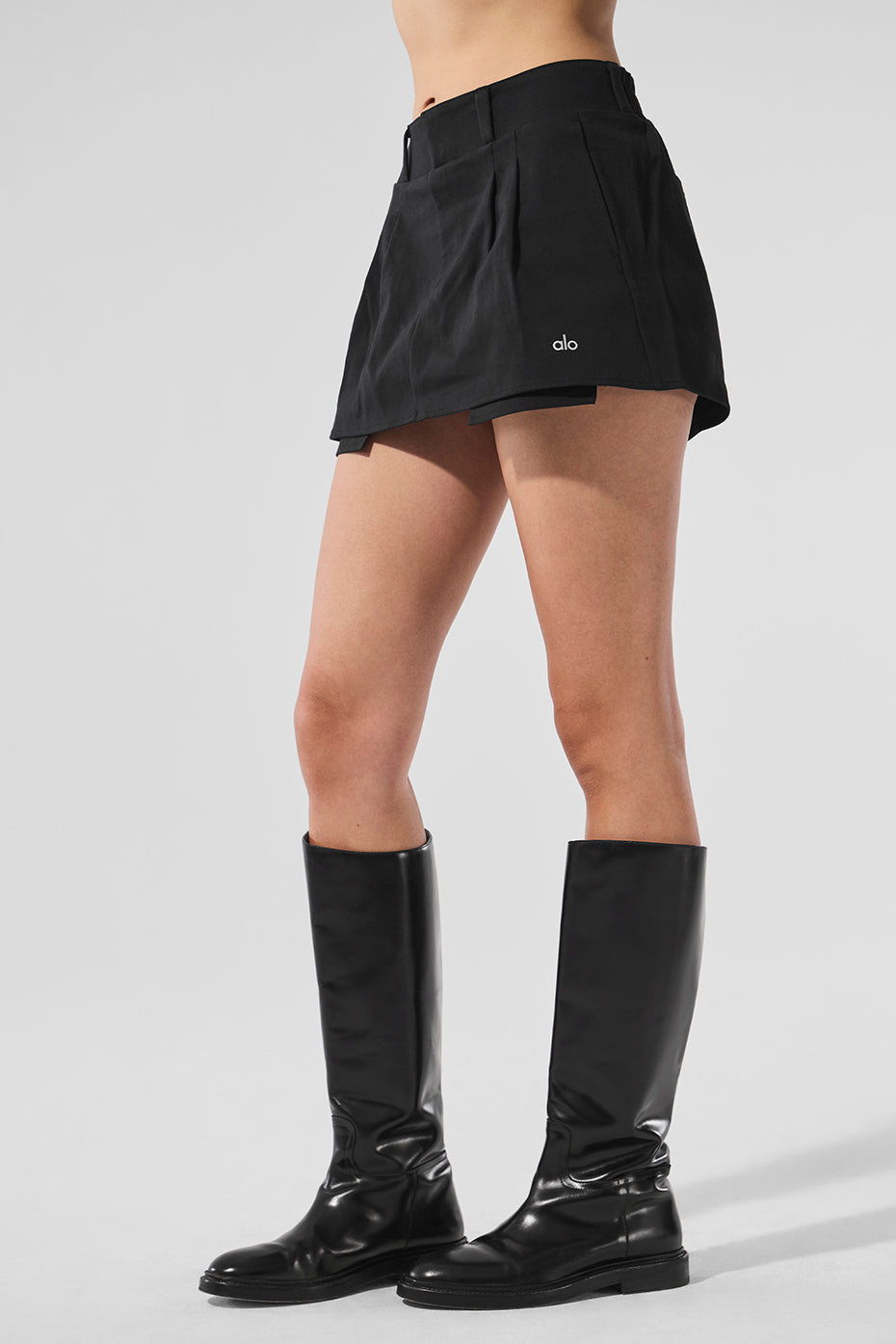 Side angle of the black mini skirt showcasing its pleated design.