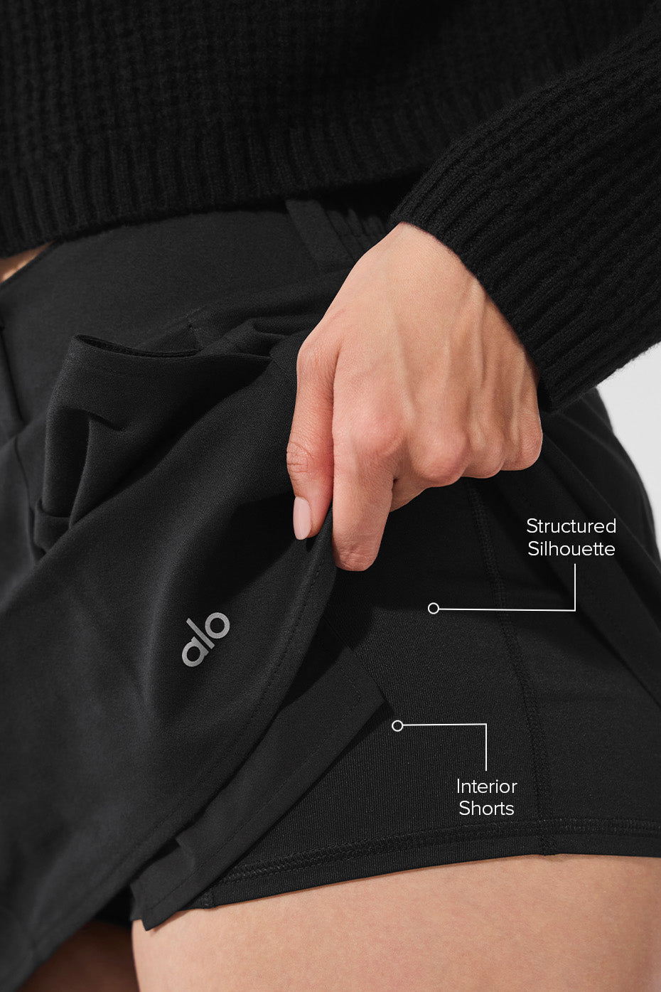 Side angle of the black mini skirt showcasing its pleated design.