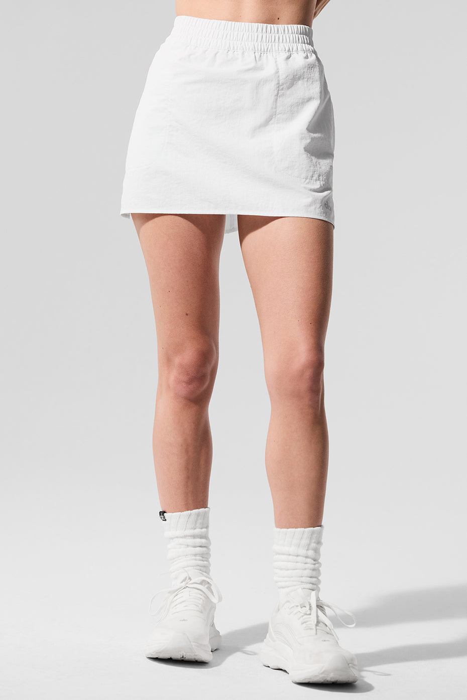 Model twisting in red tennis skirt, demonstrating built-in short coverage