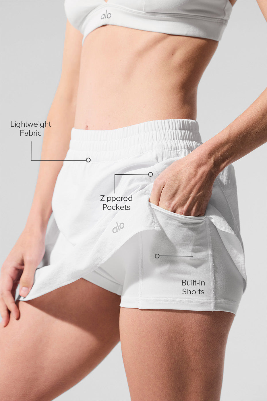 Model twisting in red tennis skirt, demonstrating built-in short coverage