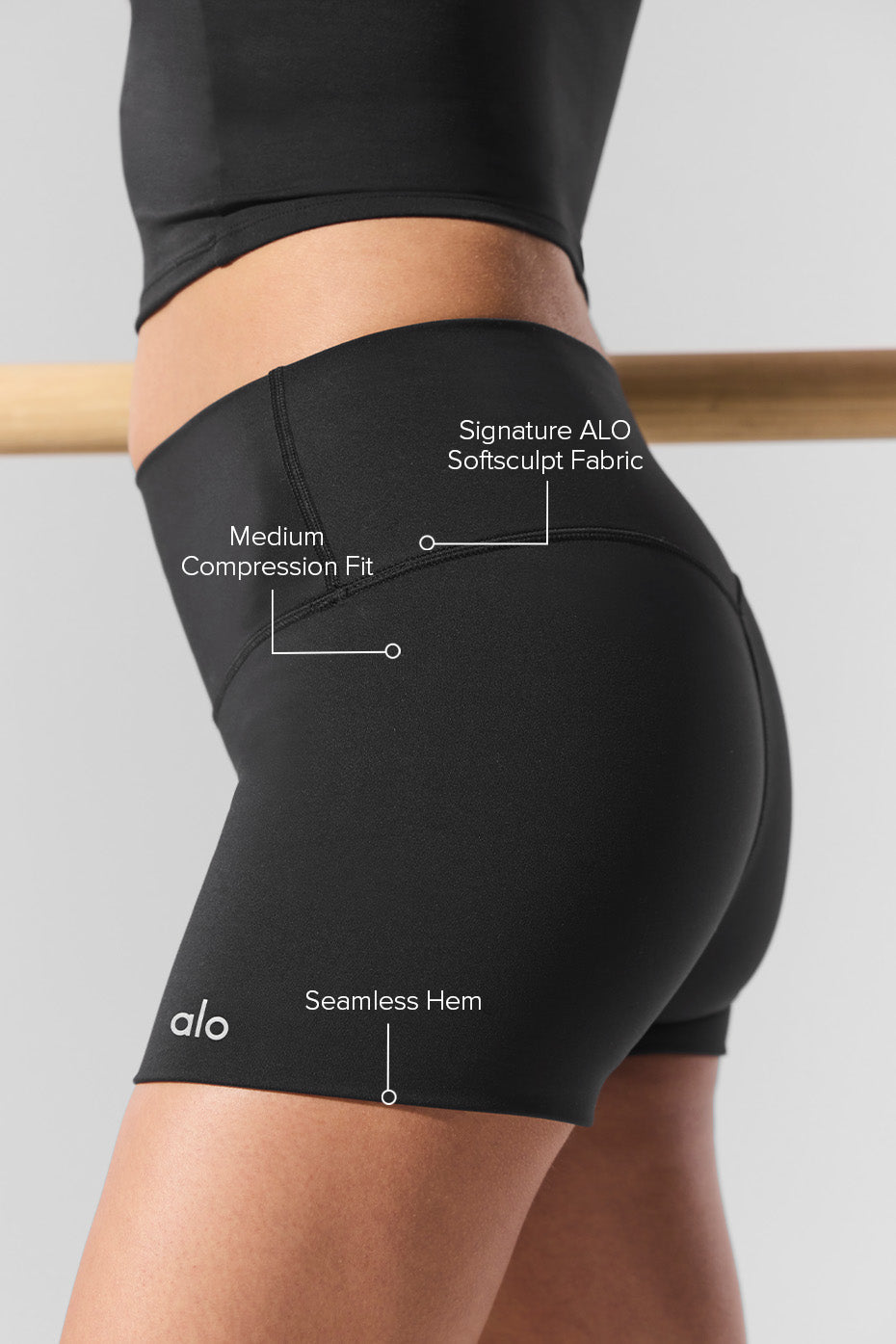 Woman wearing black high waisted shorts outdoors, stretching