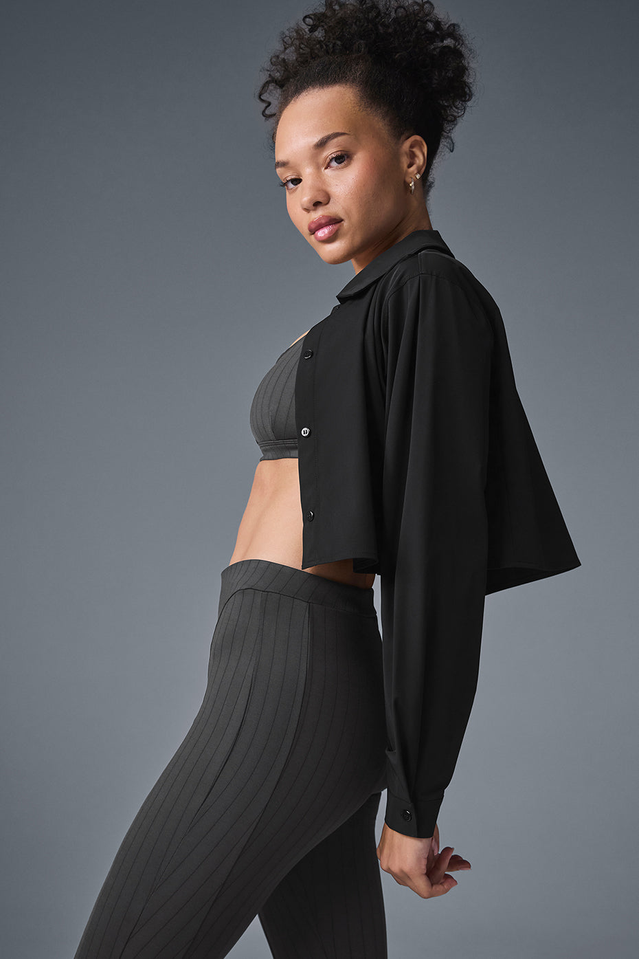 Model wearing the cropped shirt over a bra top, demonstrating its versatility.