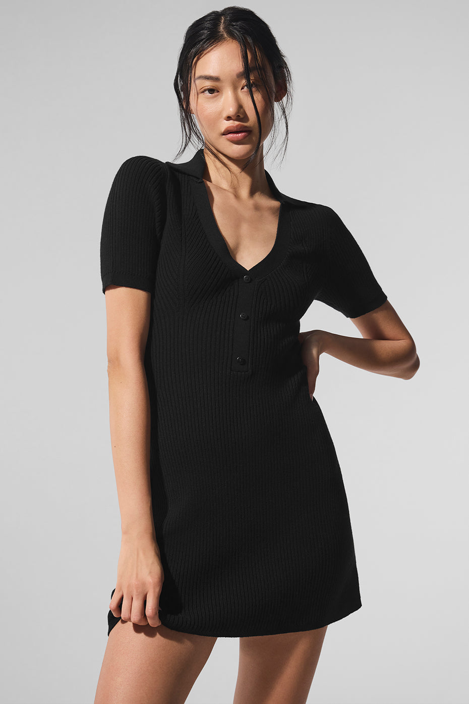 Front view of black sweater dress styled with ankle boots on a sunny Charleston street