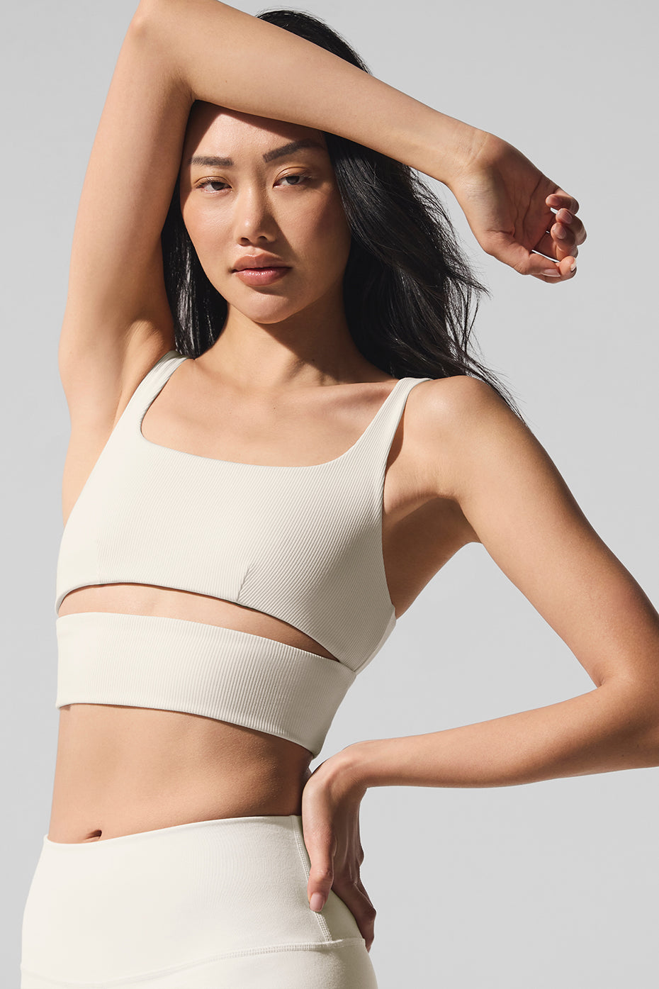 Side profile of model pairing ivory slit bra with high-waist leggings outdoors