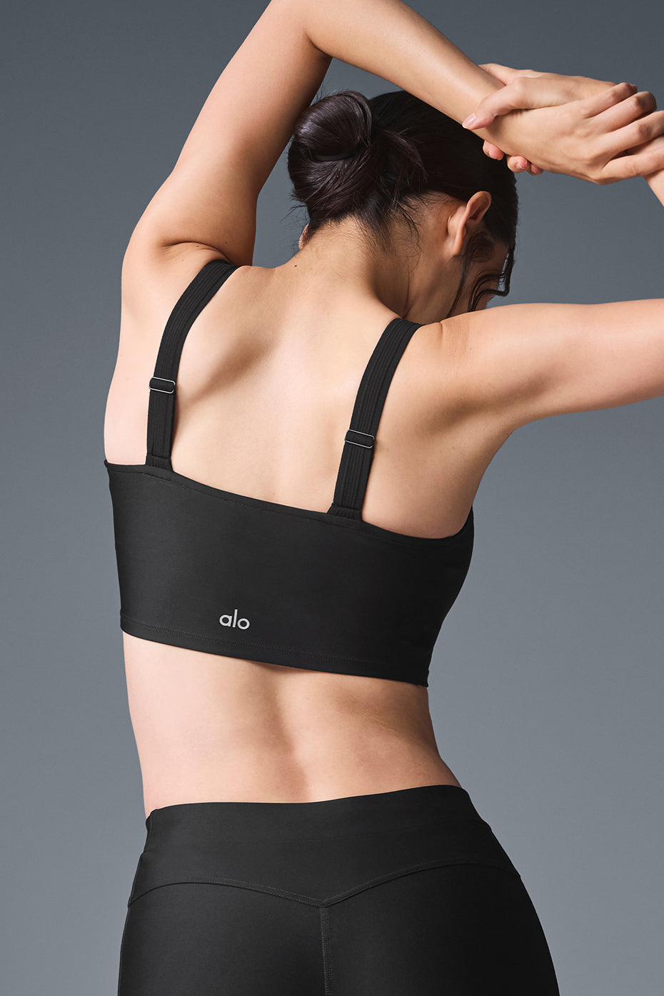 Model wearing the sports bra tank while stretching indoors
