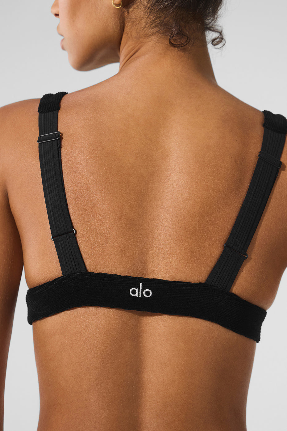 Front view of black corduroy bra styled for layering with wide-leg trousers