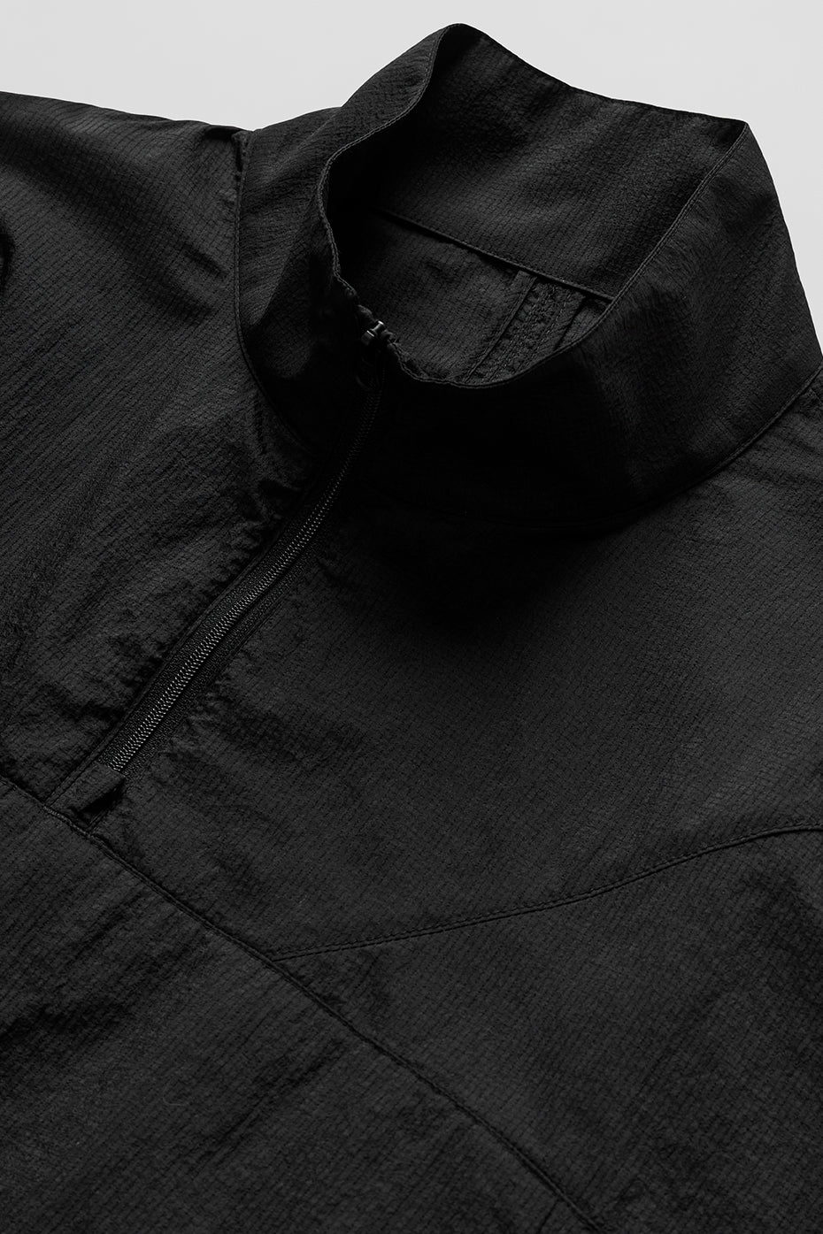 Close-up front zip feature on quarter zip top worn in casual urban setting