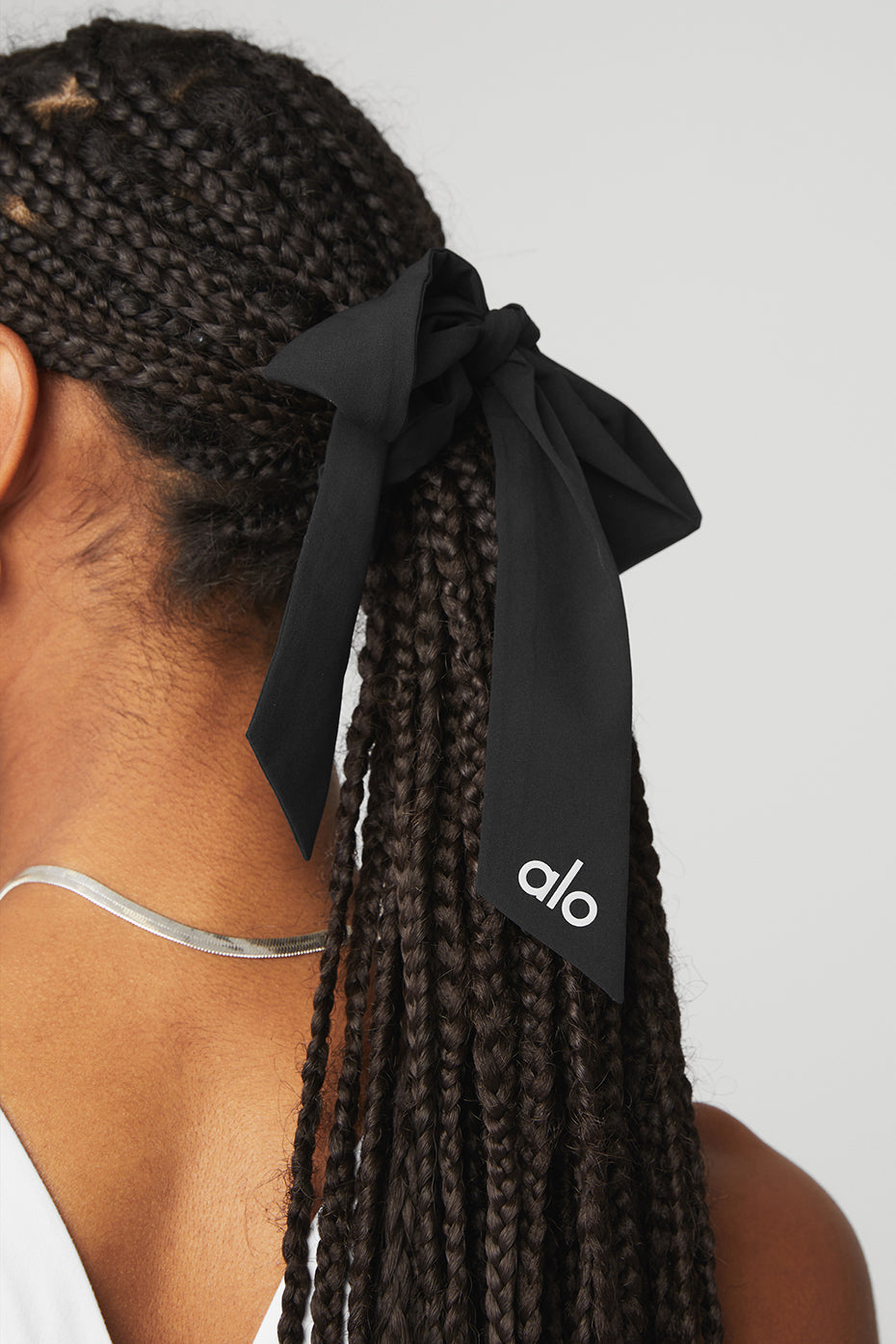 Model wearing a black bow scrunchie, highlighting its versatility.