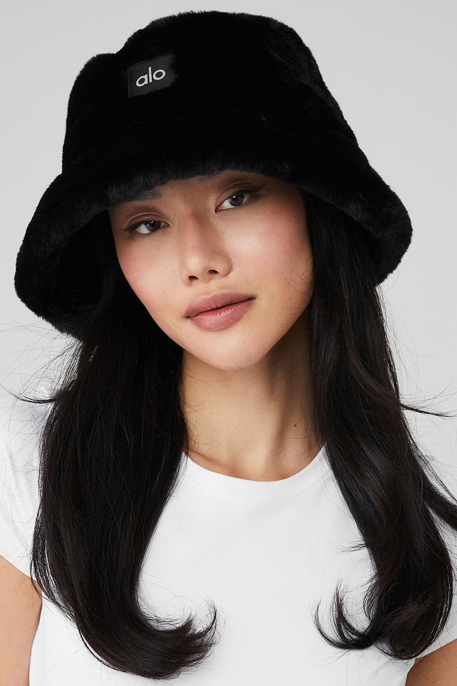 Cozy black faux fur bucket hat worn outdoors in winter.