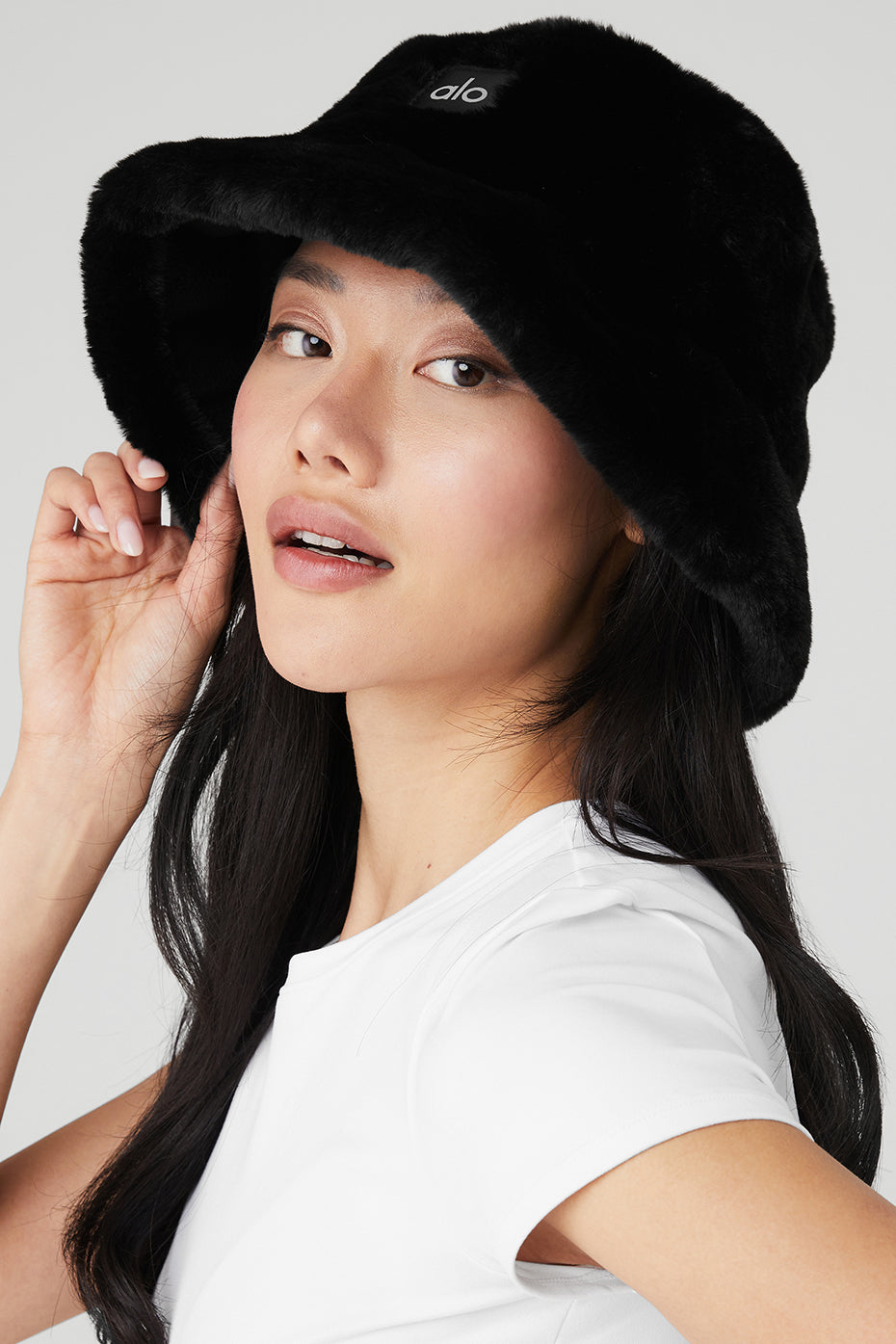 Cozy black faux fur bucket hat worn outdoors in winter.