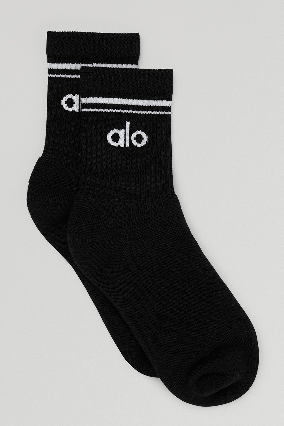 Unisex half crew socks in black and white worn with sneakers.