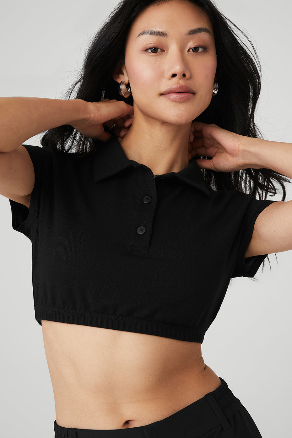 Model wearing fitted crop polo tee with high-waisted white trousers
