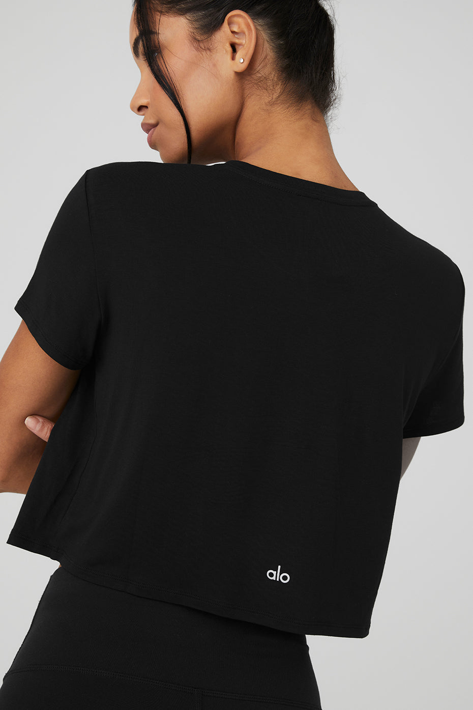 Front view of black cropped t-shirt styled with high-waisted jeans.