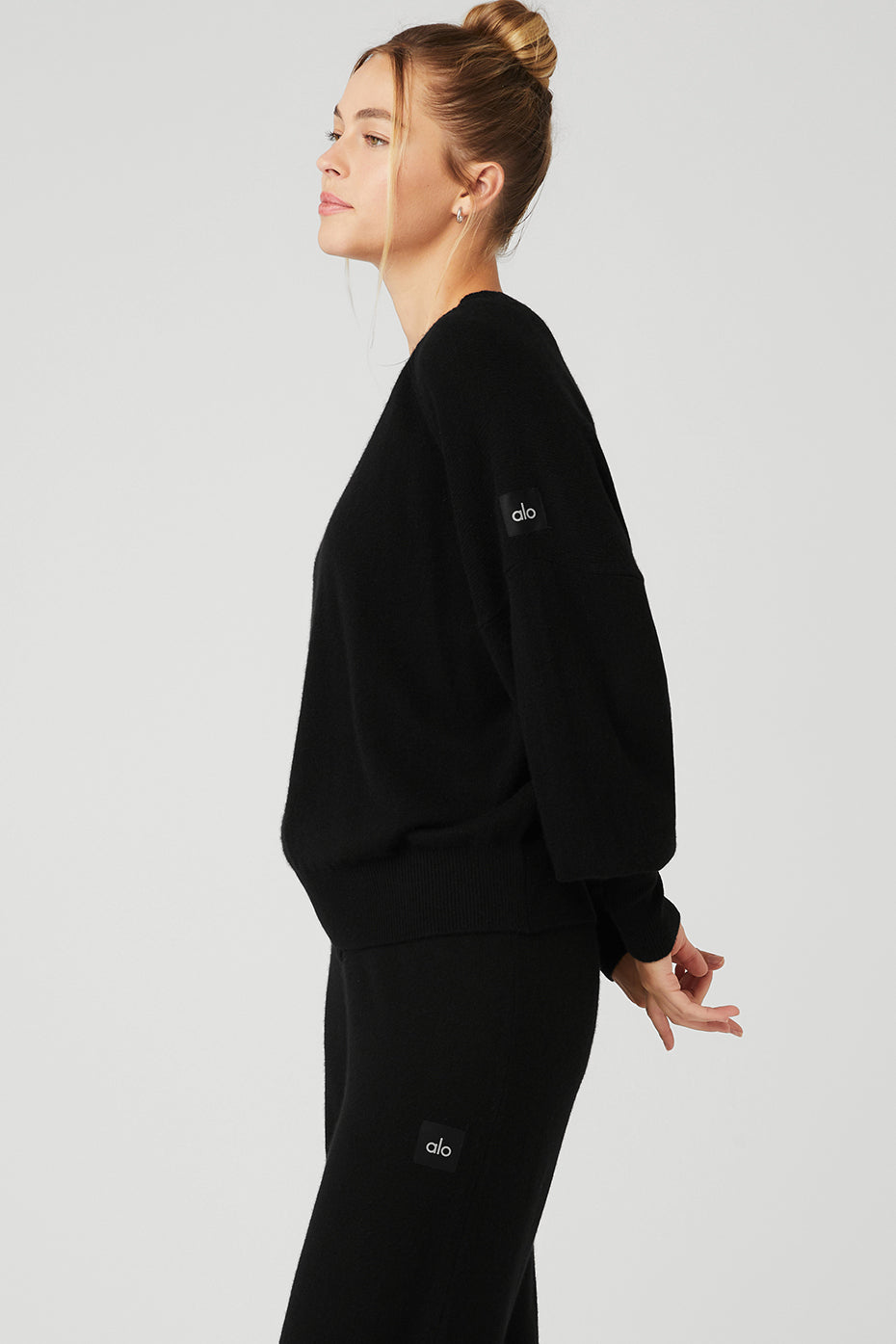 Lifestyle image of model wearing black crewneck cashmere sweater outdoors