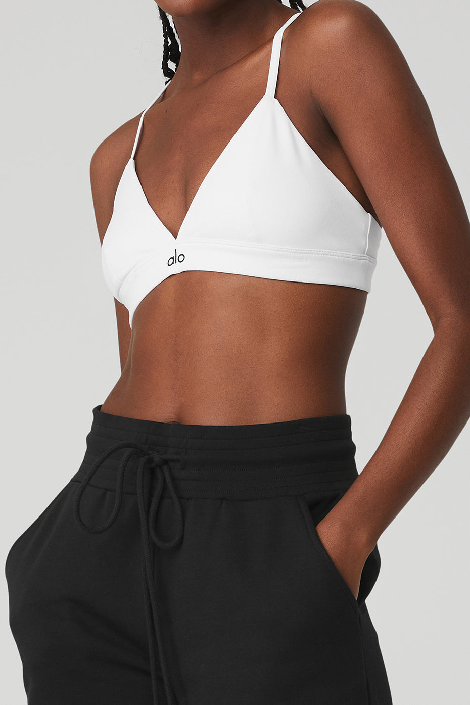 Side view of black high-waist shorts styled with slides and bra top outdoors